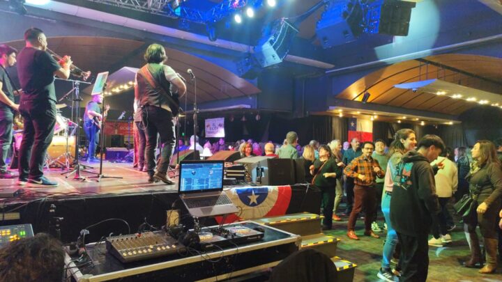 Banda en vivo y público bailando en la Gran Fonda Enjoy Viña del Mar. Bandera chilena y equipo DJ en escenario.