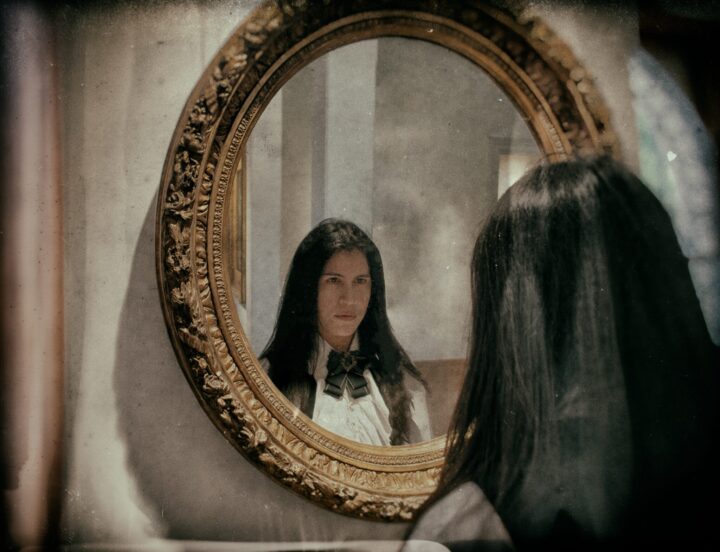 Beralibes mira su reflejo en un espejo antiguo, simbolizando los instintos y la dualidad de "Tu Sangre".