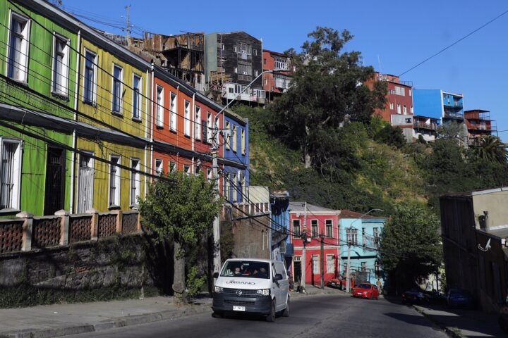 Valparaíso: Calle Carampangue con casas coloridas en cerro. Vía con baches y grietas, previo a su proyecto de mejoramiento vial.