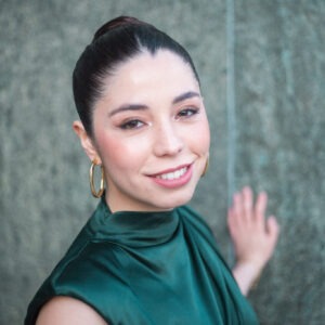 Florencia Berner, protagonista de "Auditoría de Amor" de TVN, sonríe. Viste top verde esmeralda y aros dorados. Interpreta a Estela.