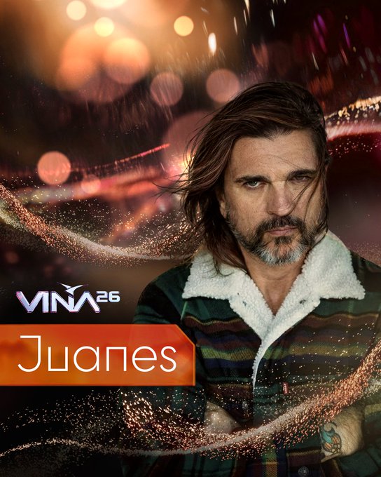 Juanes, artista confirmado para Viña 2026. Pelo largo, barba, chaqueta a cuadros. Fondo festivo con luces.