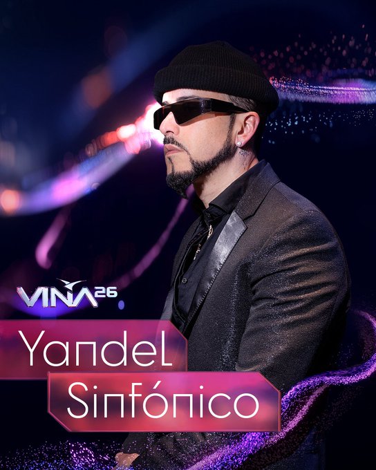 Yandel Sinfónico, artista confirmado Viña 2026. Viste gorro, gafas, blazer. Fondo oscuro con luces y logo Viña 26.